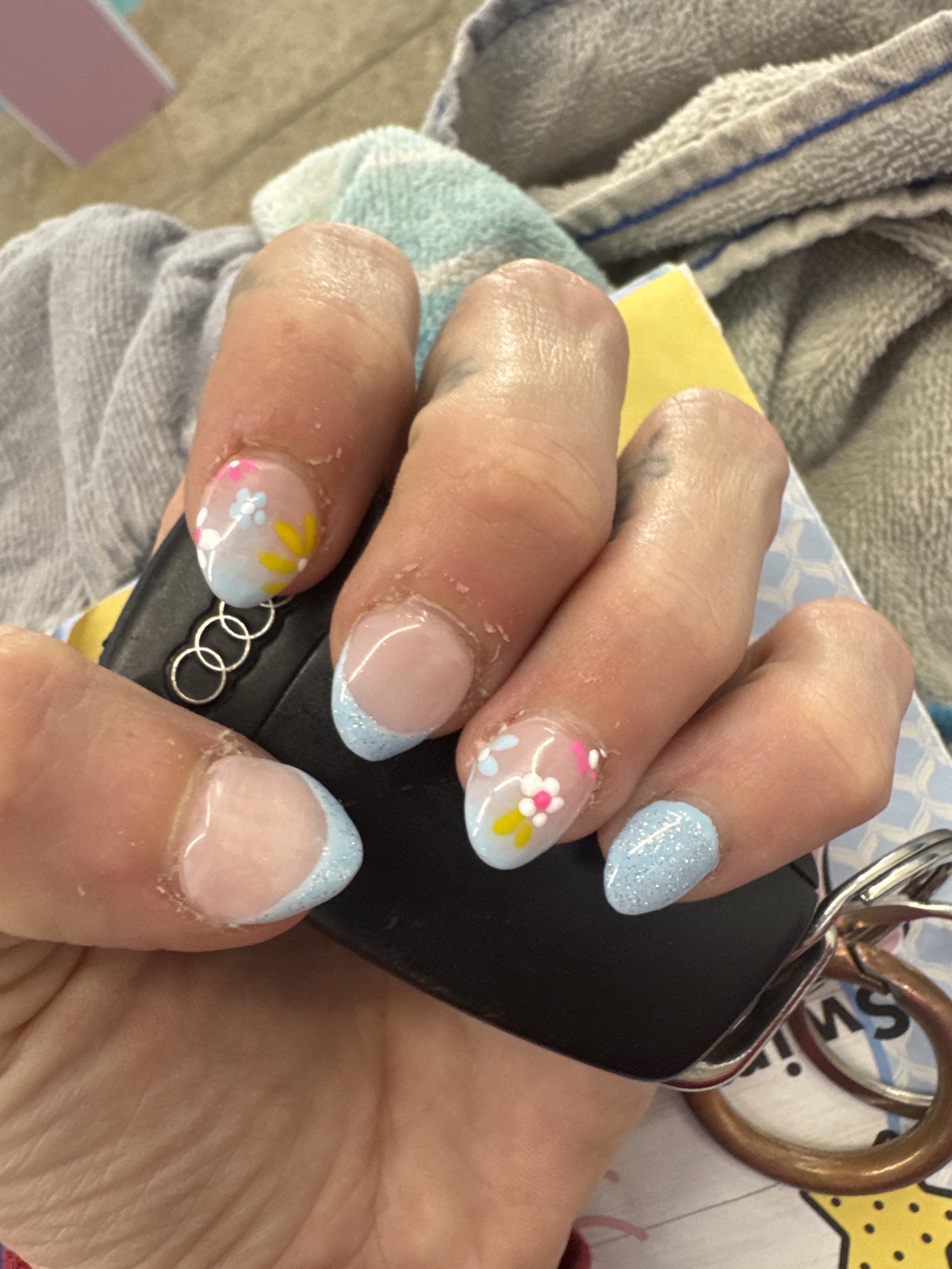 Pastel blue glitter French tips with hand-painted flowers, done at T&T