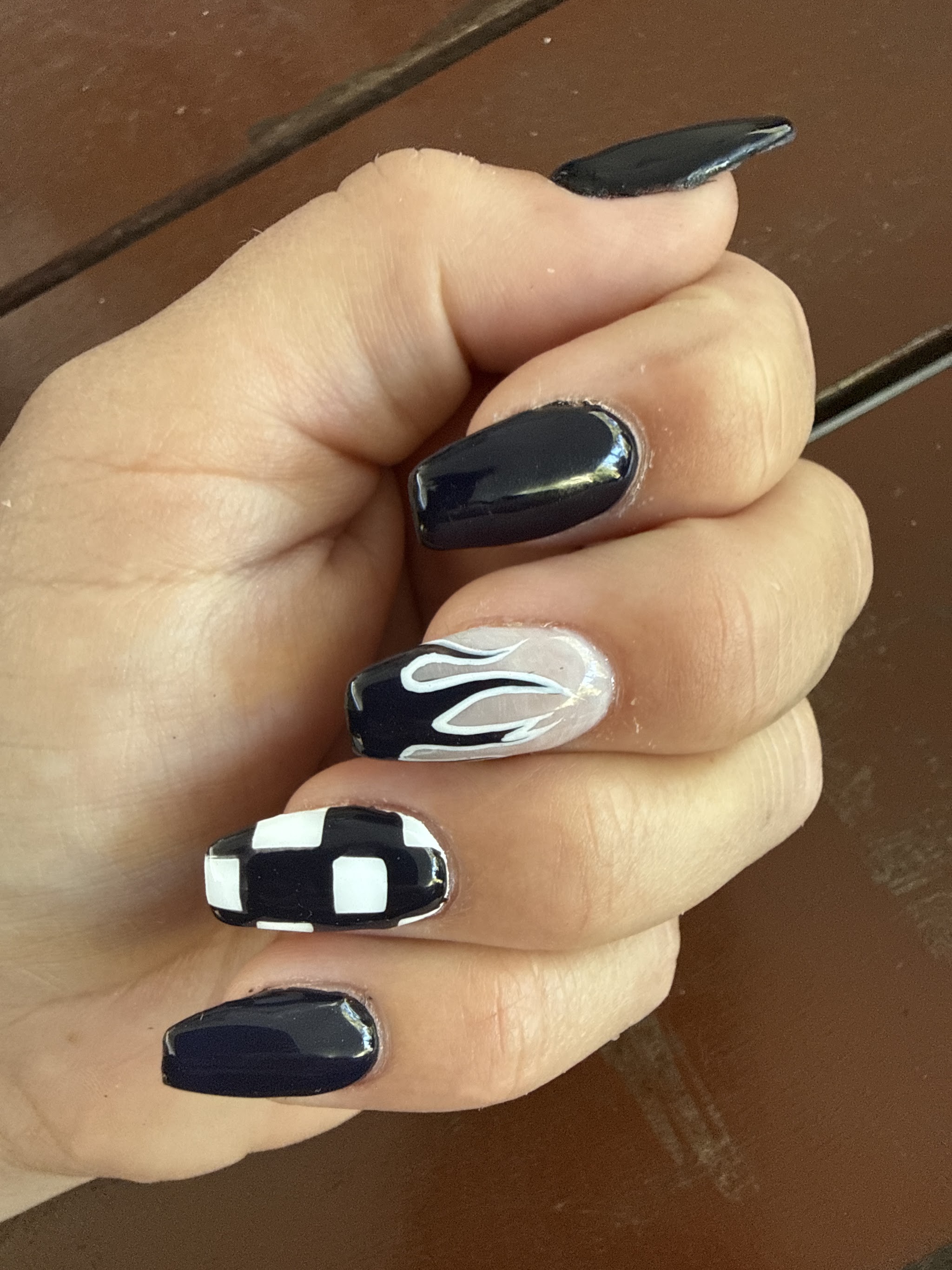 Black gel set with a checkerboard accent nail and painted flames